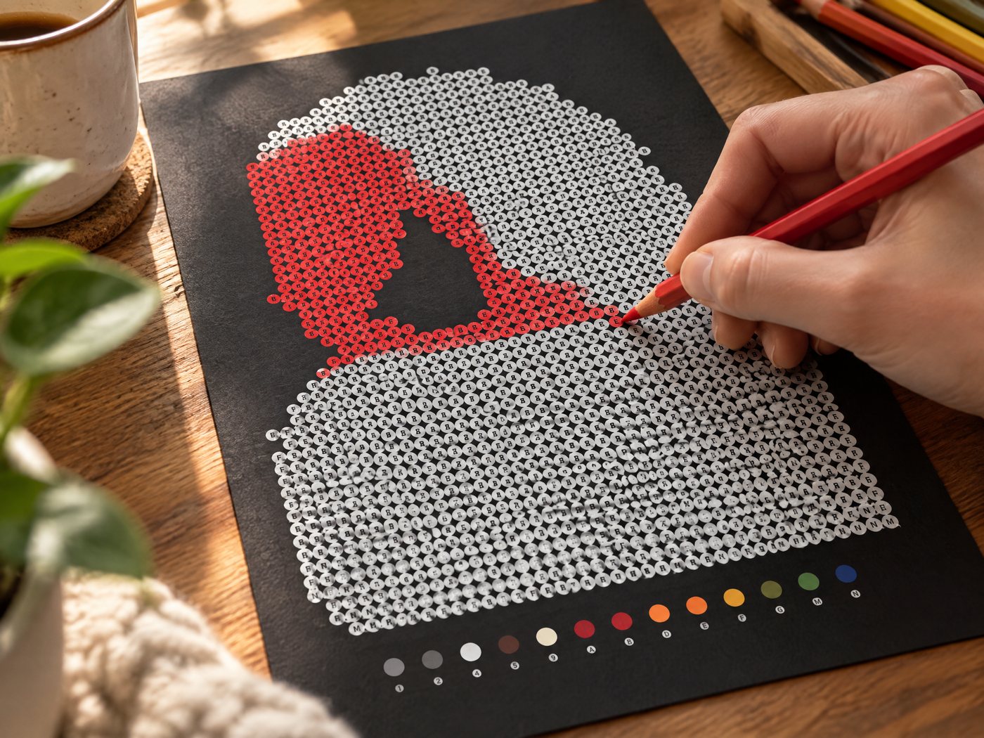 Coloring the dots of a black paper color by number page with colored pencils